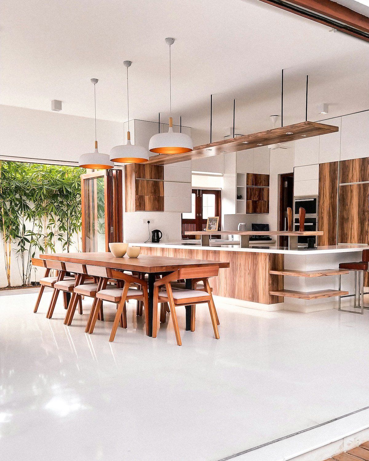 Japandi dining room and kitchen with clean lined solid wood dining table neutral palette warm pendant lighting and natural materials